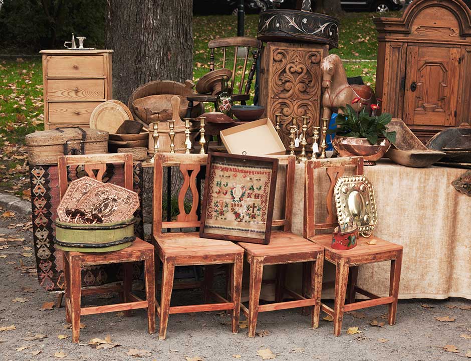 An outdoor display of antique furniture, brassware and collectables from a house clearance